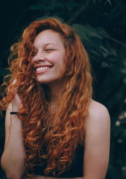 An attractive young woman with bright white teeth smiling broadly